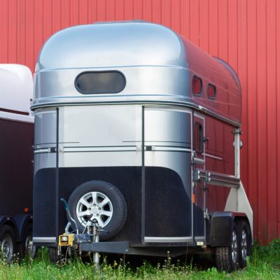 Picture of Several horse transportation trailers parked on the grass in front of red painted wooden house